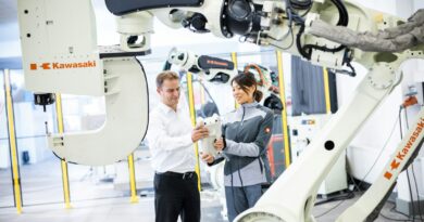 En mand og en kvinde står foran en industrirobot i et værksted
